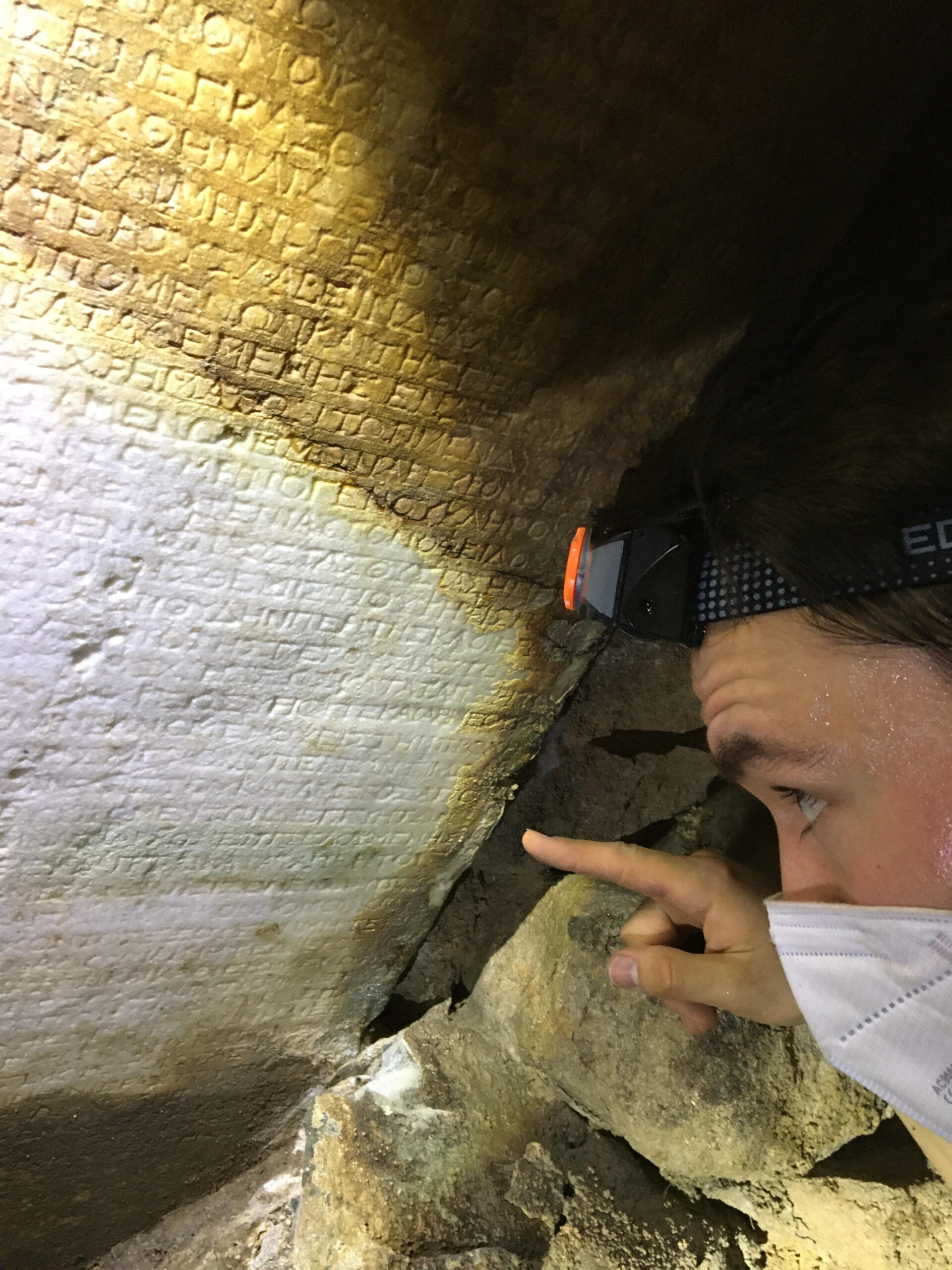 Julian untersucht mit Stirnlampe die Inschrift im Kanal